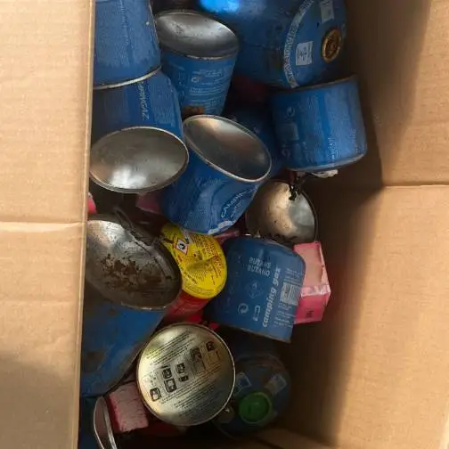 Photographie d'un tas de bouteilles de gaz sur un convoyeur dans un centre de tri